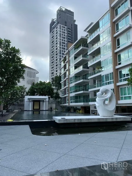 Condominium for sale in Khlong Toei, Bangkok - Modern low-rise condominium exterior with water feature and sculptural artwork.