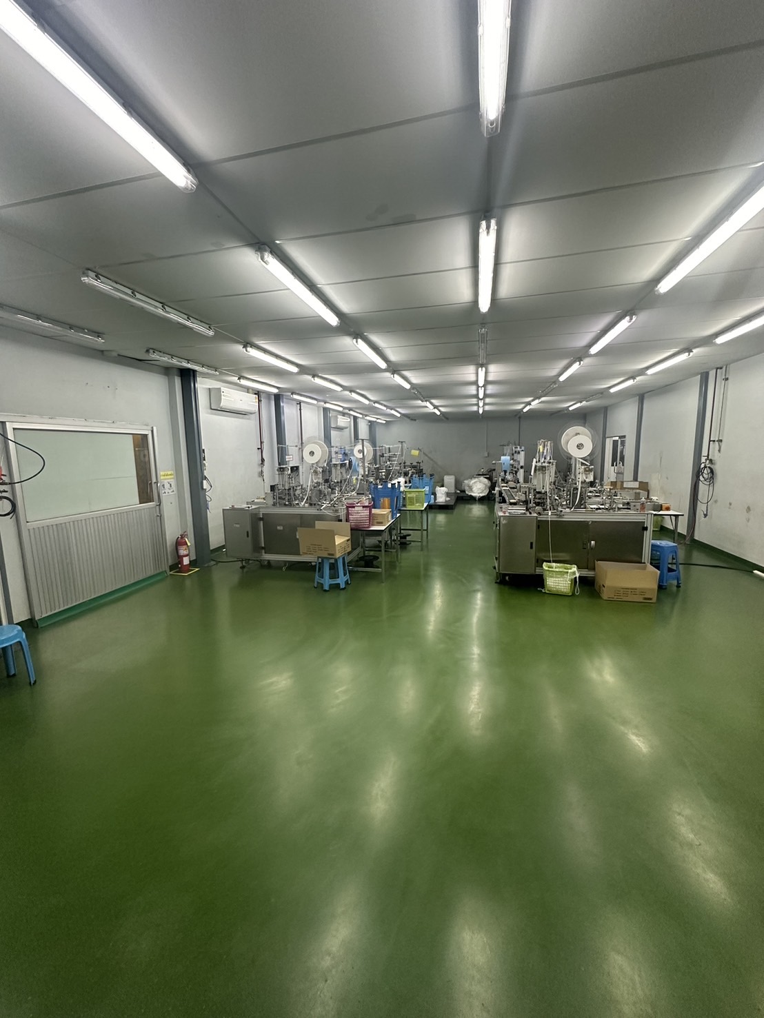 Warehouse for rent or sale in Lam Luk Ka, Pathum Thani - Long clean room with industrial machines, green epoxy floor and ceiling strip lights.