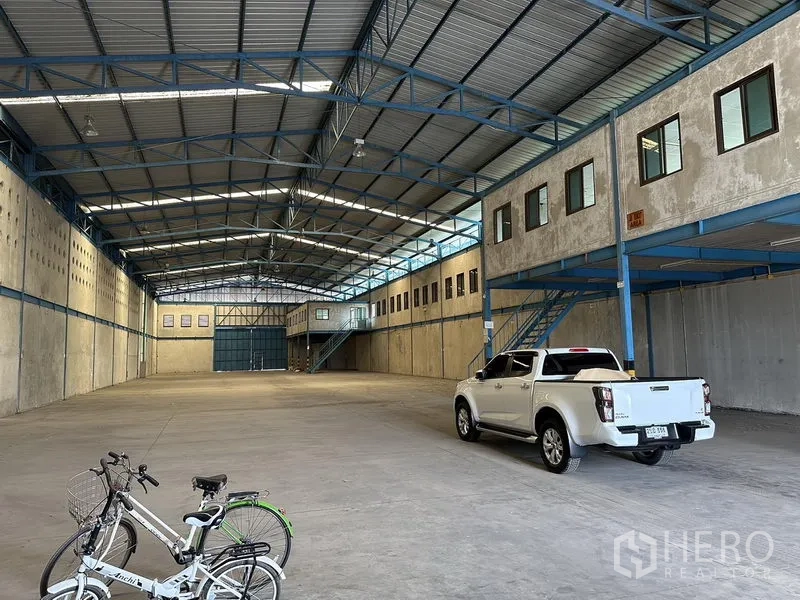 Warehouse for rent in Bang Phli, Samut Prakan - Deep central aisle of the warehouse with pickup truck and bicycles under a metal roof structure.