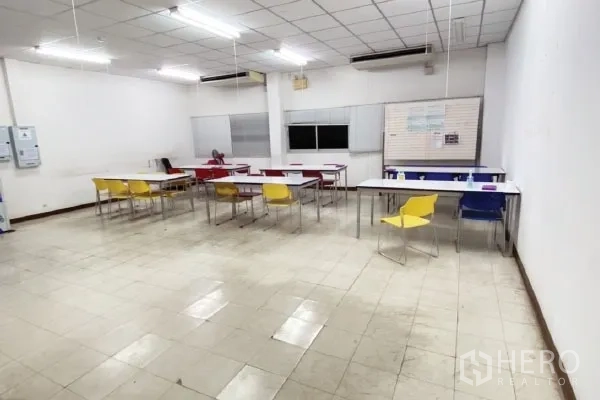 Factory for sale in Rayong - Staff canteen or training room with tiled floor, fluorescent lighting and multi-colored chairs.