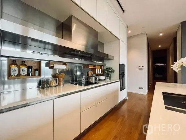 Condominium for sale in Pathum Wan, Bangkok - Sleek gourmet kitchen with white cabinetry, stainless backsplash and a long stone counter in a luxury Bangkok condo.