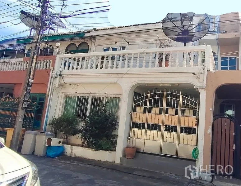 联排别墅 出租在Watthana, Bangkok - 曼谷瓦他那区两层联排屋外观，带大门车棚与阳台。
