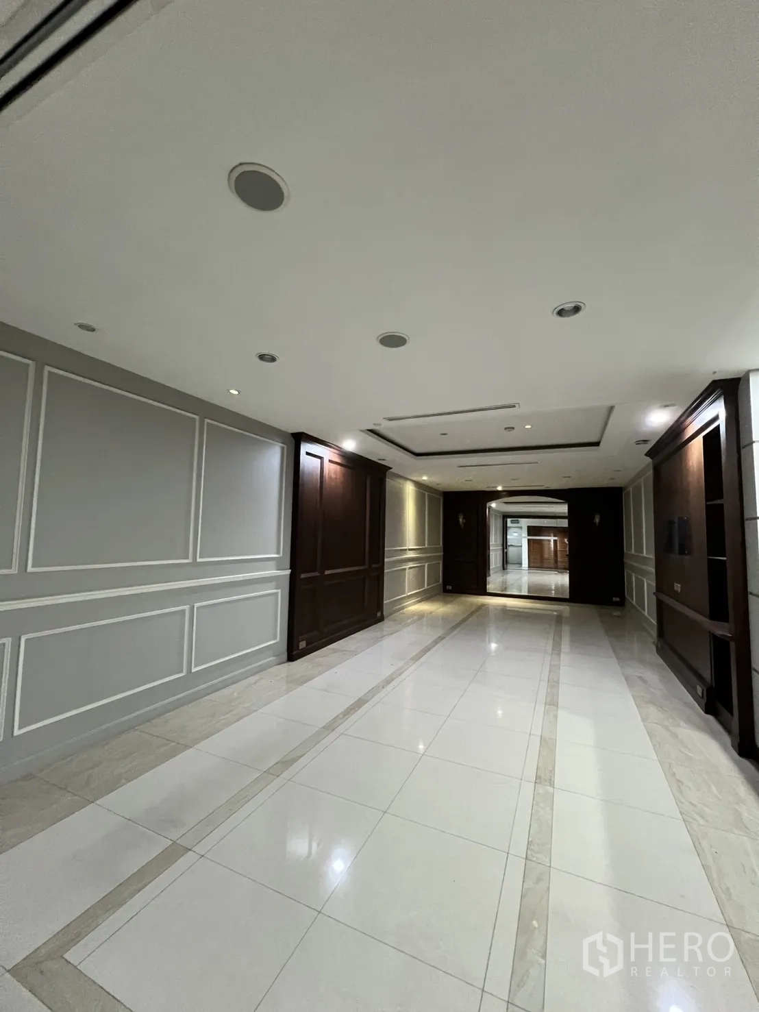 Office Space for rent in Watthana, Bangkok - Long hallway with tiled floors, wall paneling, and recessed lighting.
