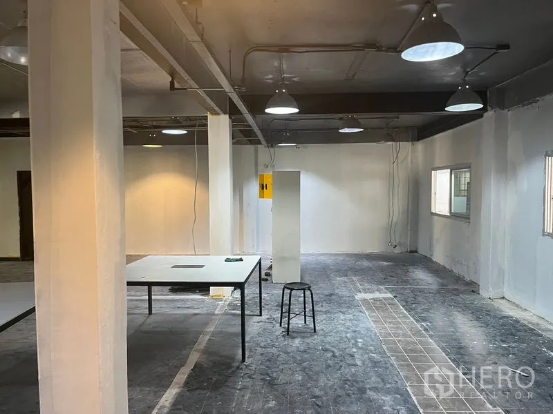 Retail Space for rent in Pathum Wan, Bangkok - Shell-condition retail floor with lighting, cable runs and a central table.