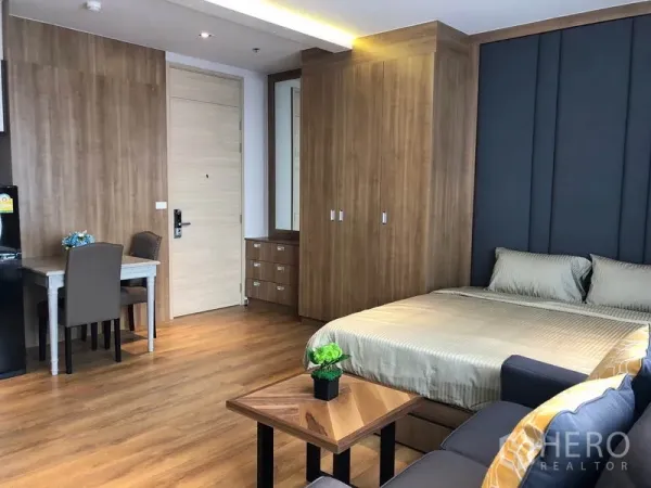 Condominium for rent in Khlong Toei, Bangkok - Built-in wardrobe, dining desk, and queen bed in wood-finished 1-bedroom condo.