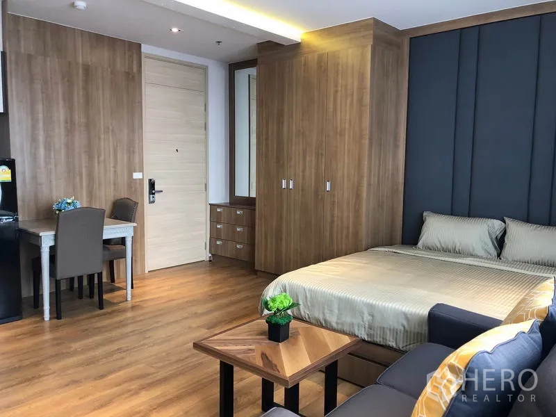 Condominium for rent in Khlong Toei, Bangkok - Built-in wardrobe, dining desk, and queen bed in wood-finished 1-bedroom condo.