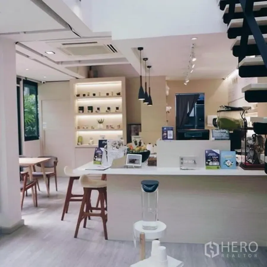 Shophouse for rent in Bang Rak, Bangkok - Bright coffee counter with display shelving, pendant lighting and stairs to a mezzanine in a Silom shophouse.