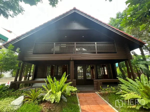 Home Office for rent in Suan Luang, Bangkok - Front view of gable-roof wooden home office with upper balcony and landscaped yard.