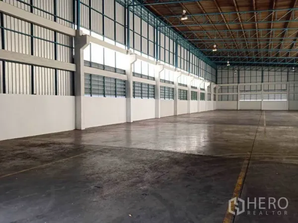 Factory for rent in Samut Prakan - Side wall view showing ventilation louver windows and clear-span floor in the factory.