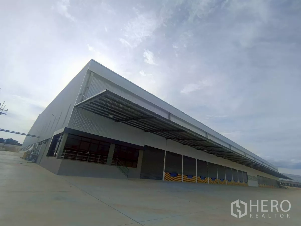 Factory for rent in Si Racha, Chon Buri - New standalone factory exterior in Si Racha with long covered loading docks and a wide concrete yard.