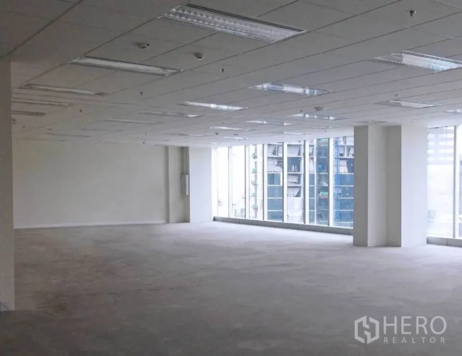 Office Space for rent in Bang Na, Bangkok - Spacious open-plan office with grid ceiling lights, carpeted floor, and large city-view windows in Bang Na, Bangkok.