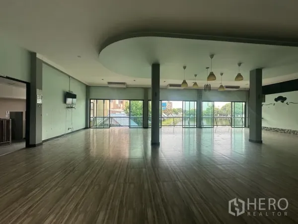 Standalone for rent in Prawet, Bangkok - Upper-floor hall facing a balcony with floor-to-ceiling glass and green city views.