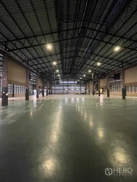 Warehouse for rent in Si Racha, Chon Buri - Open production floor under a steel roof with multiple bays and lighting.