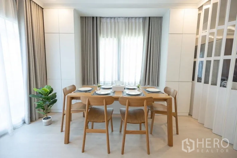 Detached House for sale in Prawet, Bangkok - Formal dining room with six-seat wooden table, built-in cabinets and soft lighting.