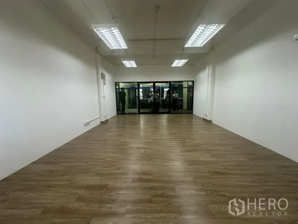 Office Space for rent in Chatuchak, Bangkok - Long rectangular office facing a glass frontage, wood-look flooring and multiple ceiling light panels.
