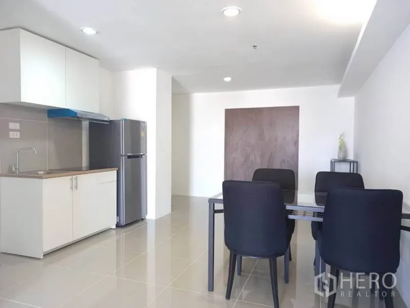 Condominium for rent in Khlong Toei, Bangkok - Open kitchenette with sink, range hood, refrigerator and a four-seat dining table.