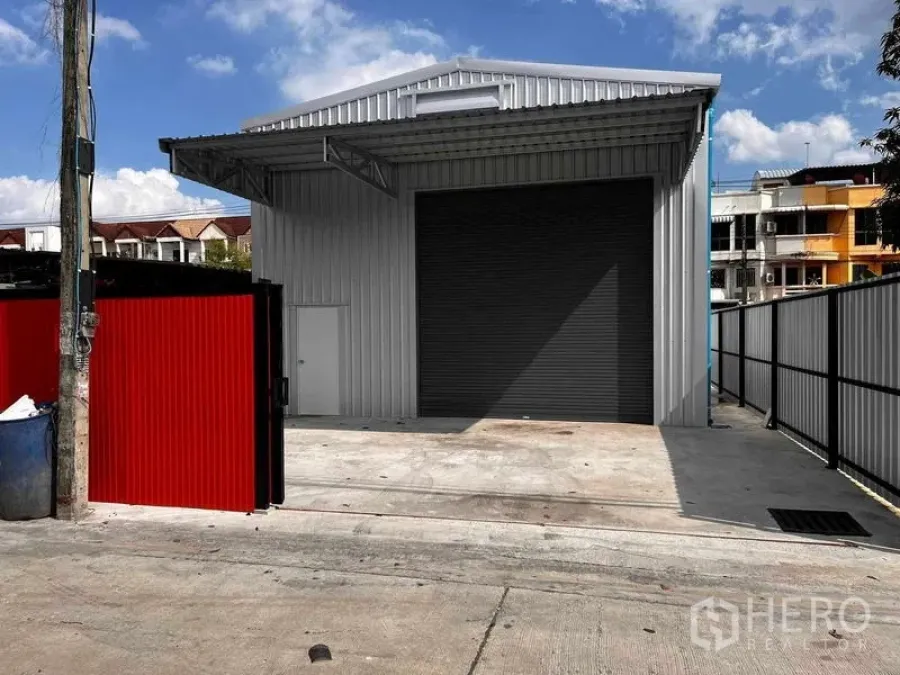 Warehouse for rent in Lat Phrao, Bangkok - Modern standalone metal-clad warehouse in Lat Phrao with large roller shutter, gated entrance and concrete loading apron.