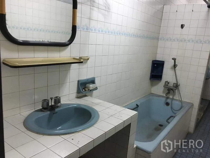 Shophouse for rent in Phra Khanong, Bangkok - Tiled bathroom with bathtub, blue sink, wall mirror, and handheld shower.