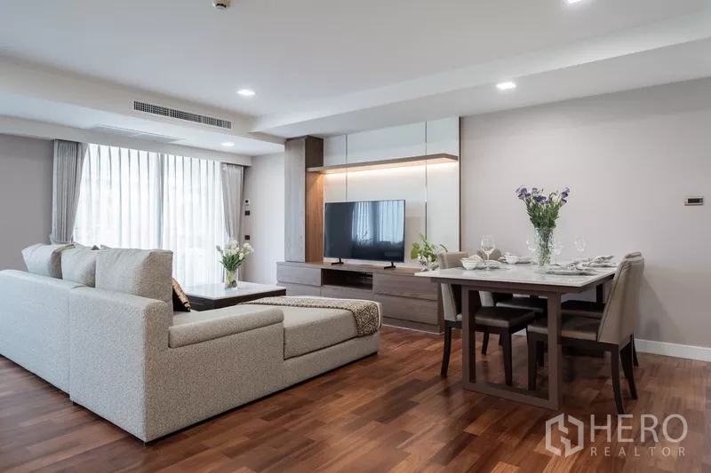 Apartment for rent - Bright open-plan living and dining with sectional sofa, TV wall and wood floors.