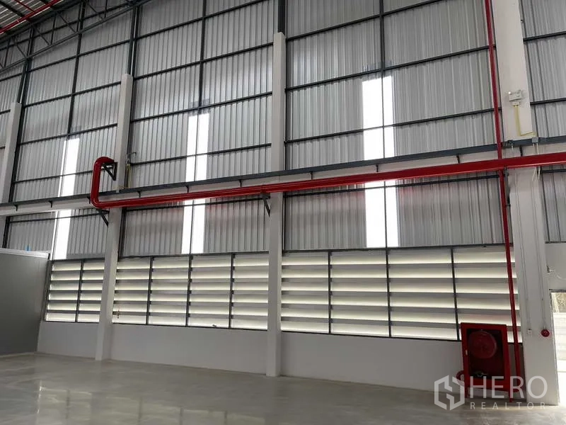 Factory for rent in Si Racha, Chon Buri - Fire safety piping and hose reel on an insulated metal wall with louvered vents.