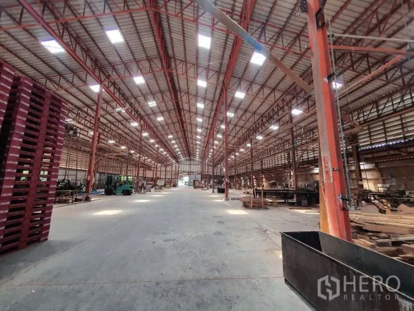 Warehouse for rent in Lam Luk Ka, Pathum Thani - Wide central aisle inside the warehouse with skylights, red steel columns and forklifts.