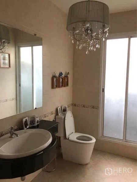 Detached House for rent or sale in Prawet, Bangkok - Bathroom with chandelier lighting, large mirror, and frosted window.