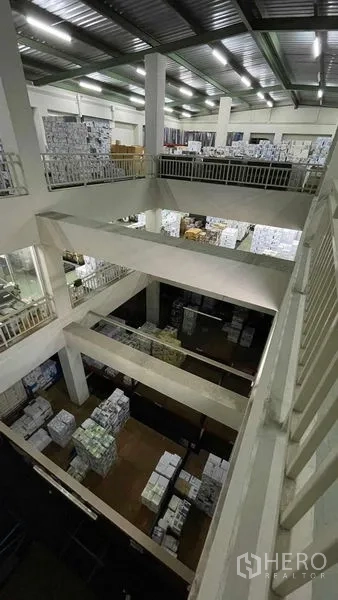 Warehouse for rent or sale in Bangkok Yai, Bangkok - Multi-level storage hall with high ceiling and stacked goods seen from mezzanine.