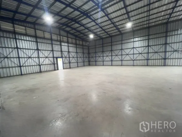 Warehouse for rent in Khlong Luang, Pathum Thani - Large warehouse interior with a high steel-frame roof, bright overhead lights, and a wide concrete floor.