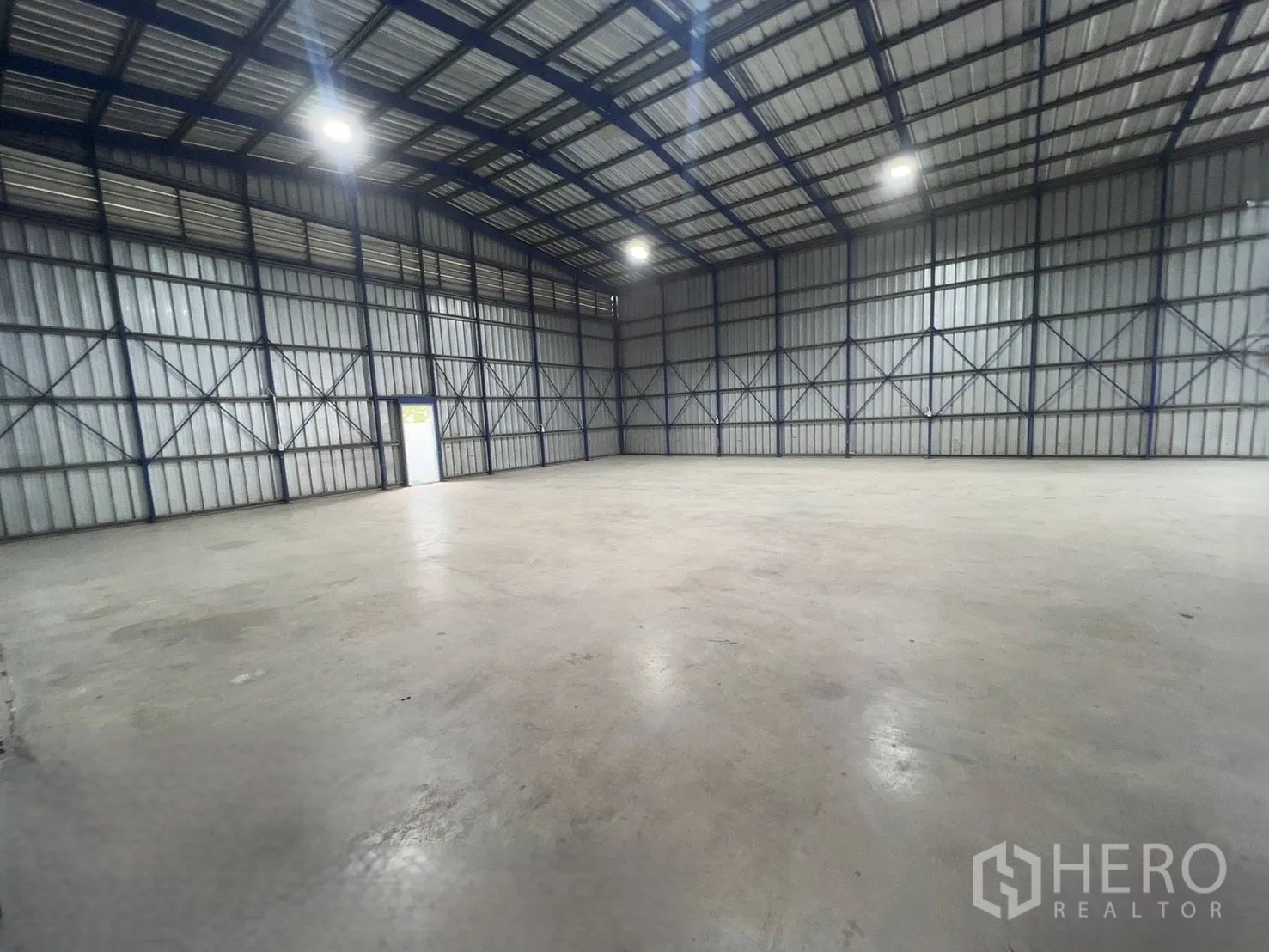 Warehouse for rent in Khlong Luang, Pathum Thani - Large warehouse interior with a high steel-frame roof, bright overhead lights, and a wide concrete floor.