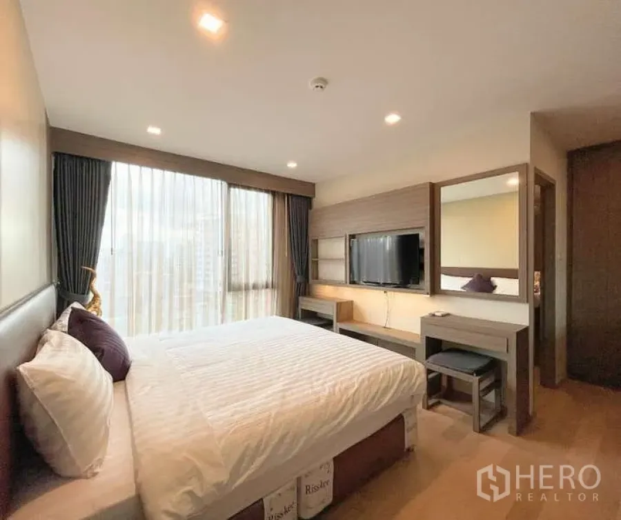 Condominium for rent - Cozy bedroom with full-height curtains, TV, and dressing table.