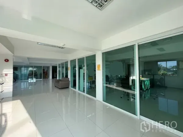 Warehouse for rent or sale in Nonthaburi - Spacious office corridor with floor-to-ceiling glass meeting rooms and seating area.