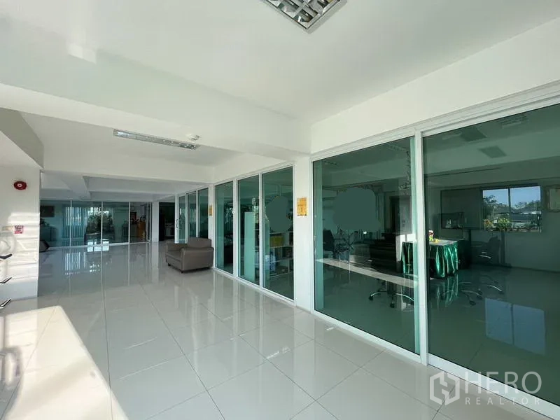 Warehouse for rent or sale in Nonthaburi - Spacious office corridor with floor-to-ceiling glass meeting rooms and seating area.