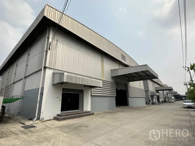 Warehouse for rent in Bang Phli, Samut Prakan - Modern industrial warehouse exterior with wide driveway and covered loading canopy in Bang Phli.