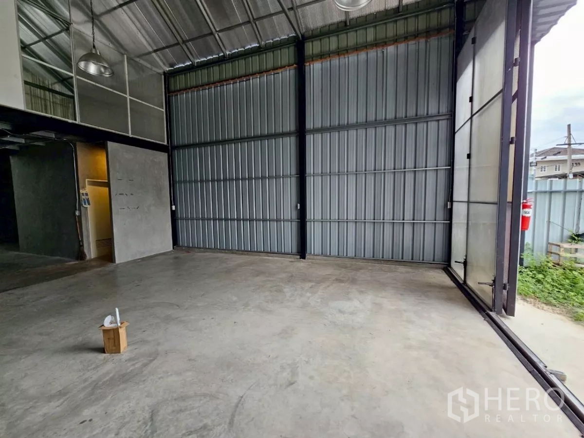 Warehouse for rent in Chatuchak, Bangkok - Ground floor storage bay with polished concrete floor and tall steel sliding gate.