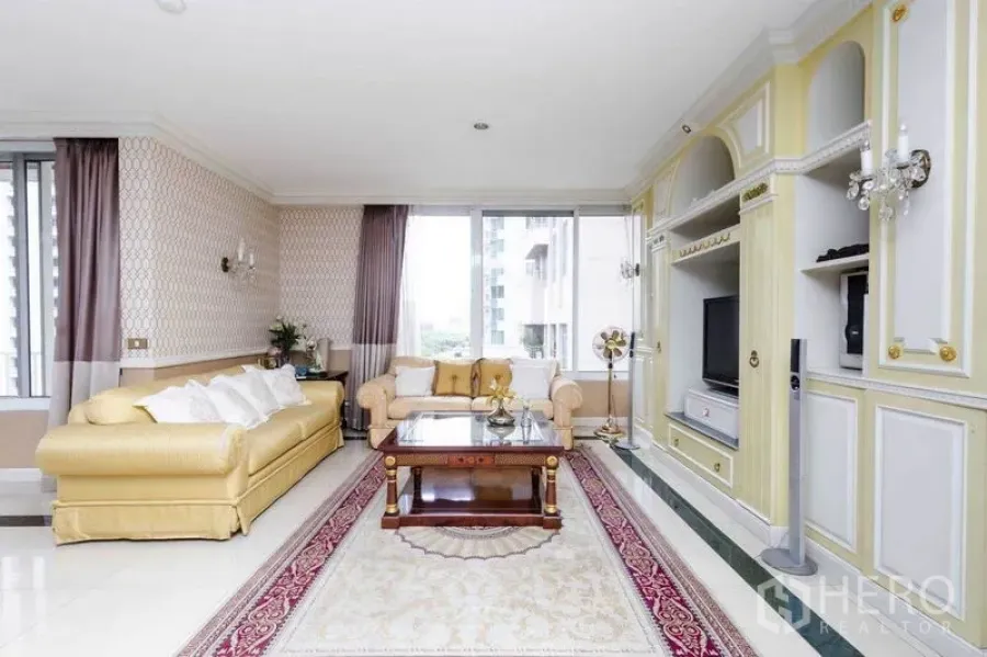 Condominium for rent or sale in Pathum Wan, Bangkok - Light-filled living room with classic built-in media wall, sofas, and city-view windows.