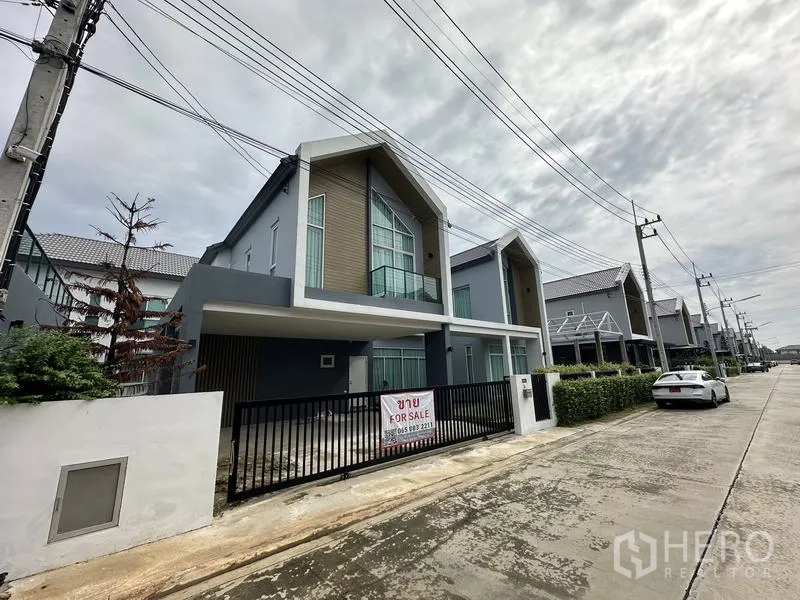 Detached House for sale in Lam Luk Ka, Pathum Thani - Angled view of the home’s facade with black metal fence and covered carport.