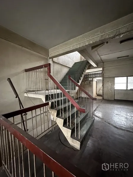 Shophouse for rent or sale in Watthana, Bangkok - Concrete stairwell with metal railings connecting multiple levels.