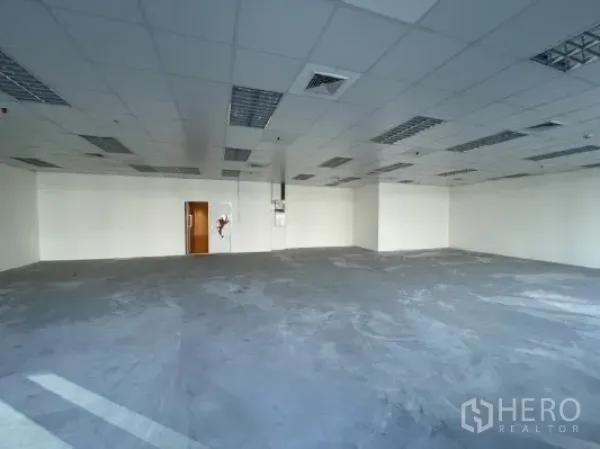 Office Space for rent in Khlong Toei, Bangkok - Unfurnished office area with white walls, drop ceiling lights, and a wooden access door.