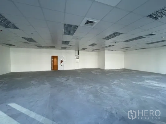 Office Space for rent in Khlong Toei, Bangkok - Unfurnished office area with white walls, drop ceiling lights, and a wooden access door.