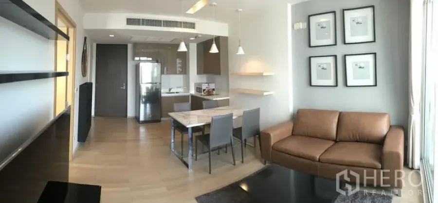 Condominium for rent in Khlong Toei, Bangkok - Panoramic view of living space showing kitchen, dining set and sofa with wood flooring at Siri at Sukhumvit