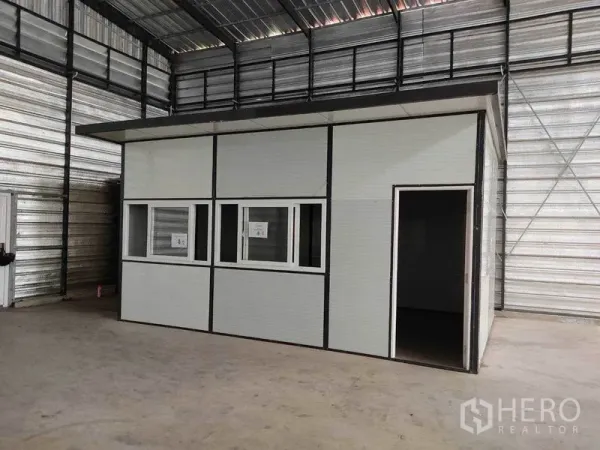 Warehouse for rent in Bang Phli, Samut Prakan - Freestanding modular office box with windows and doorway situated inside the warehouse.