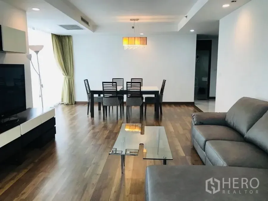 Condominium for rent in Pathum Wan, Bangkok - Open living and dining space with sofa set, glass table, chandelier and wide windows.