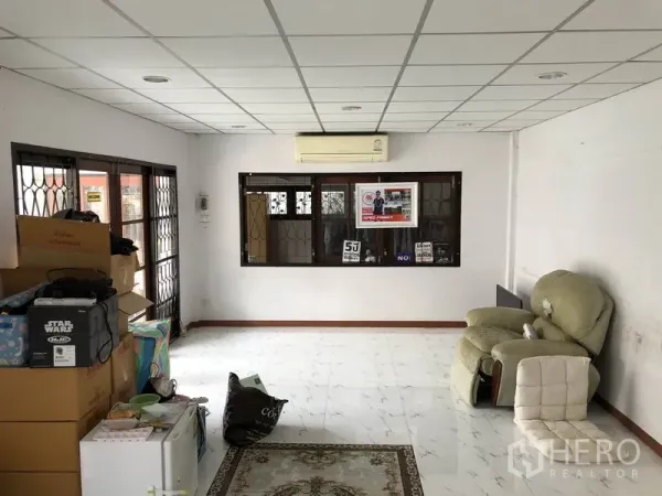 บ้าน ขายในPak Kret, Nonthaburi - ห้องนั่งเล่นโปร่ง พื้นกระเบื้องสีขาว ฝ้าเพดานไฟดาวน์ไลท์และแอร์