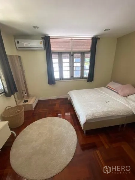 Detached House for rent in Khlong Toei, Bangkok - Bedroom with double bed, window curtains, air conditioner and round rug.