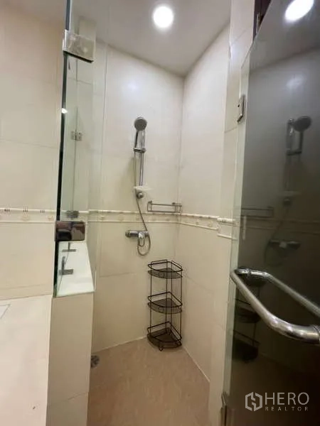 Apartment for rent in Khlong Toei, Bangkok - Glass-enclosed shower with handheld showerhead in a tiled bathroom.