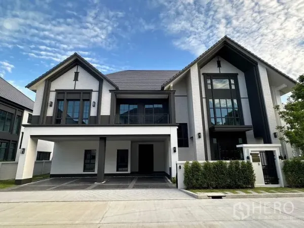 Detached House for rent or sale in Bang Phli, Samut Prakan - Contemporary detached house facade with pitched roofs, large windows and a spacious covered carport in a gated estate.