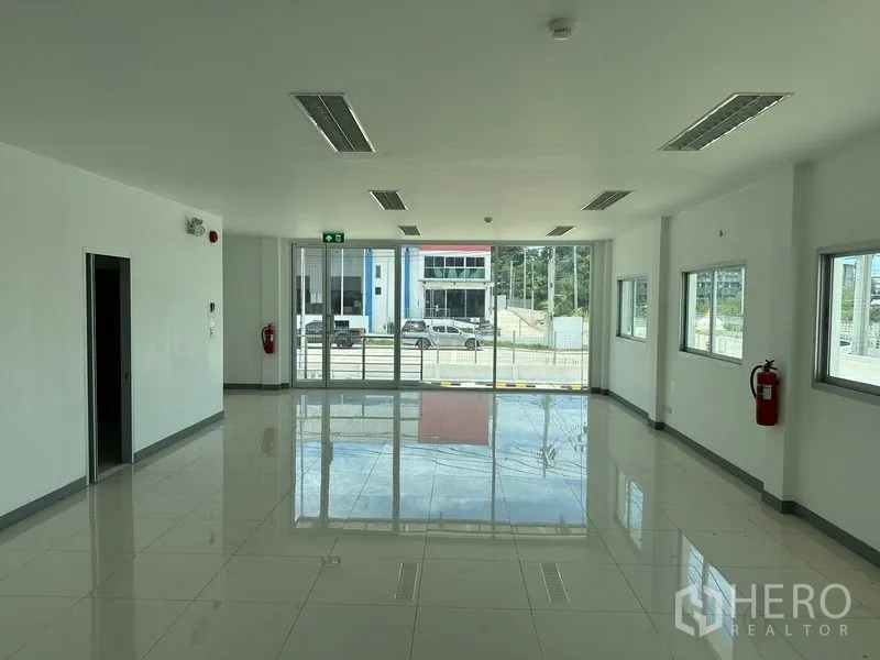Factory for rent in Mueang Samut Prakan, Samut Prakan - Bright tiled office floor with large windows and glass frontage overlooking the site.