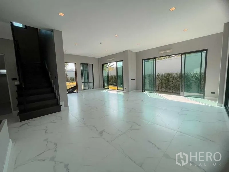 Detached House for sale in Mueang Nonthaburi, Nonthaburi - Bright open-plan living area with marble-look floors, sliding glass doors, and staircase.