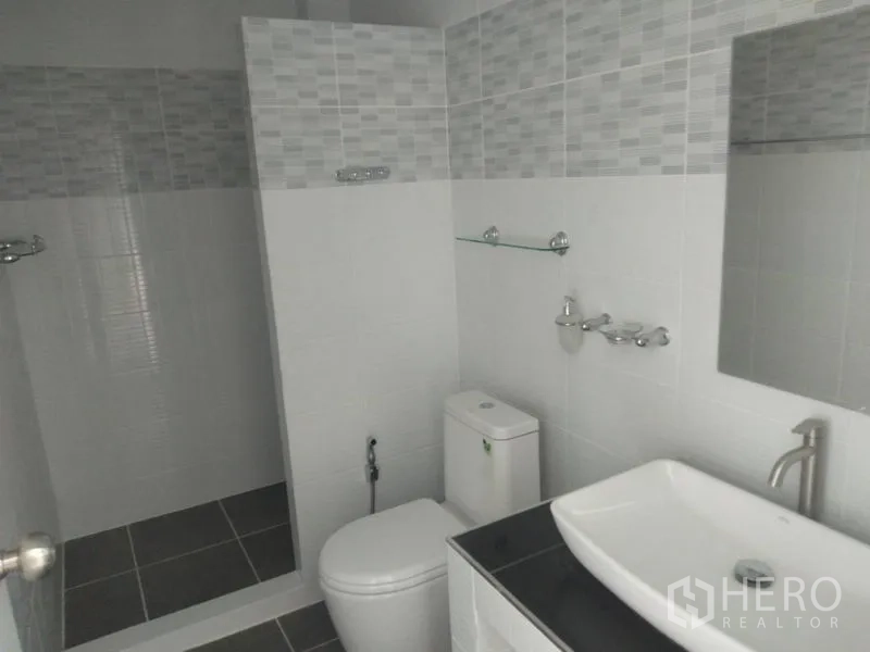 Factory for rent or sale in Lam Luk Ka, Pathum Thani - Clean tiled bathroom with walk-in shower, vanity and toilet.