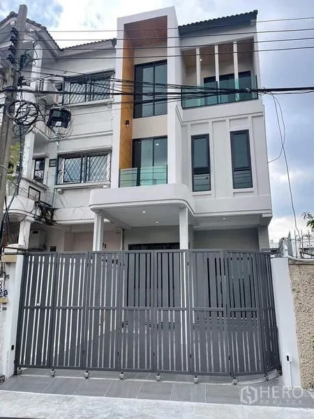 联排别墅 出售在Watthana, Bangkok - 联排别墅正面特写，大窗与安全金属门